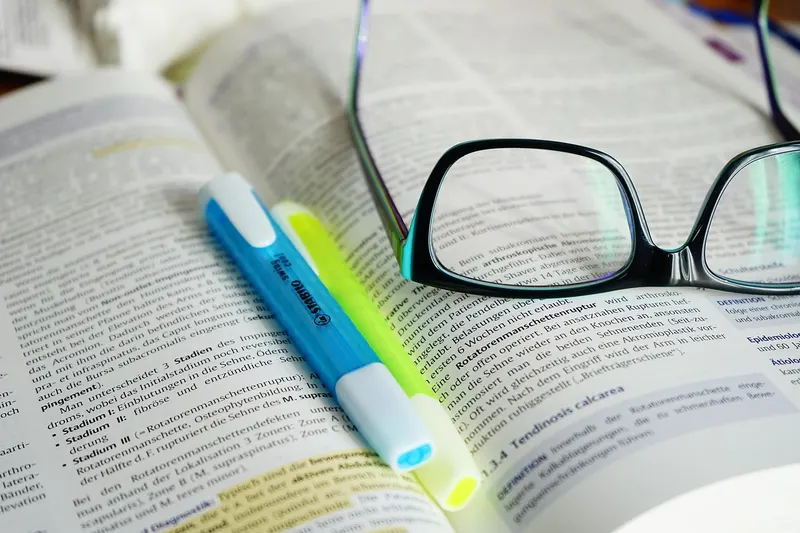 Highlighter pens and reading glasses resting on an open reference book, like an AI picking out the key lines from its sources.