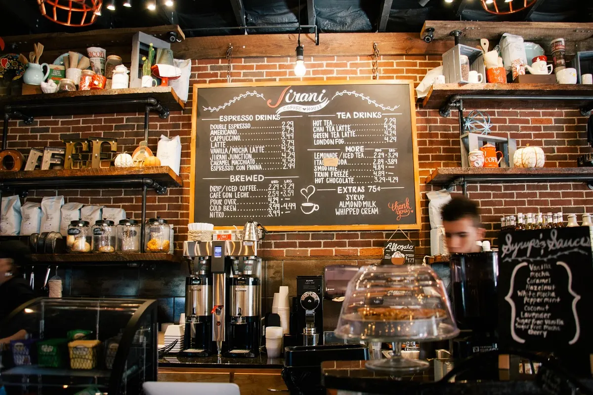 A busy independent coffee shop counter with a chalkboard menu and espresso machines, the kind of local business that lives on its reviews.