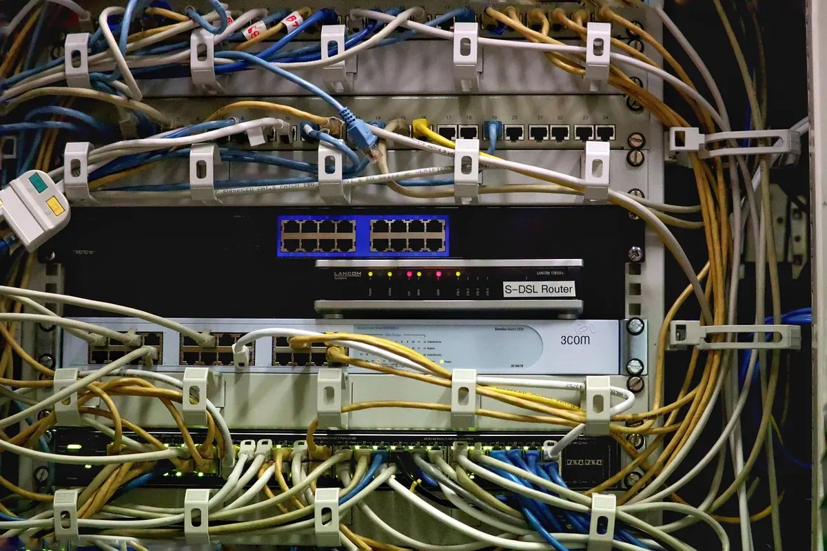 A rack of network switches and a router with dozens of patch cables plugged in, the kind of kit that keeps hosted websites online.