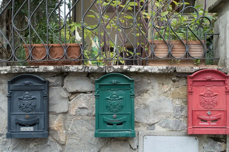 Three wall-mounted letterboxes in black, green and red, each one a different place post can be delivered