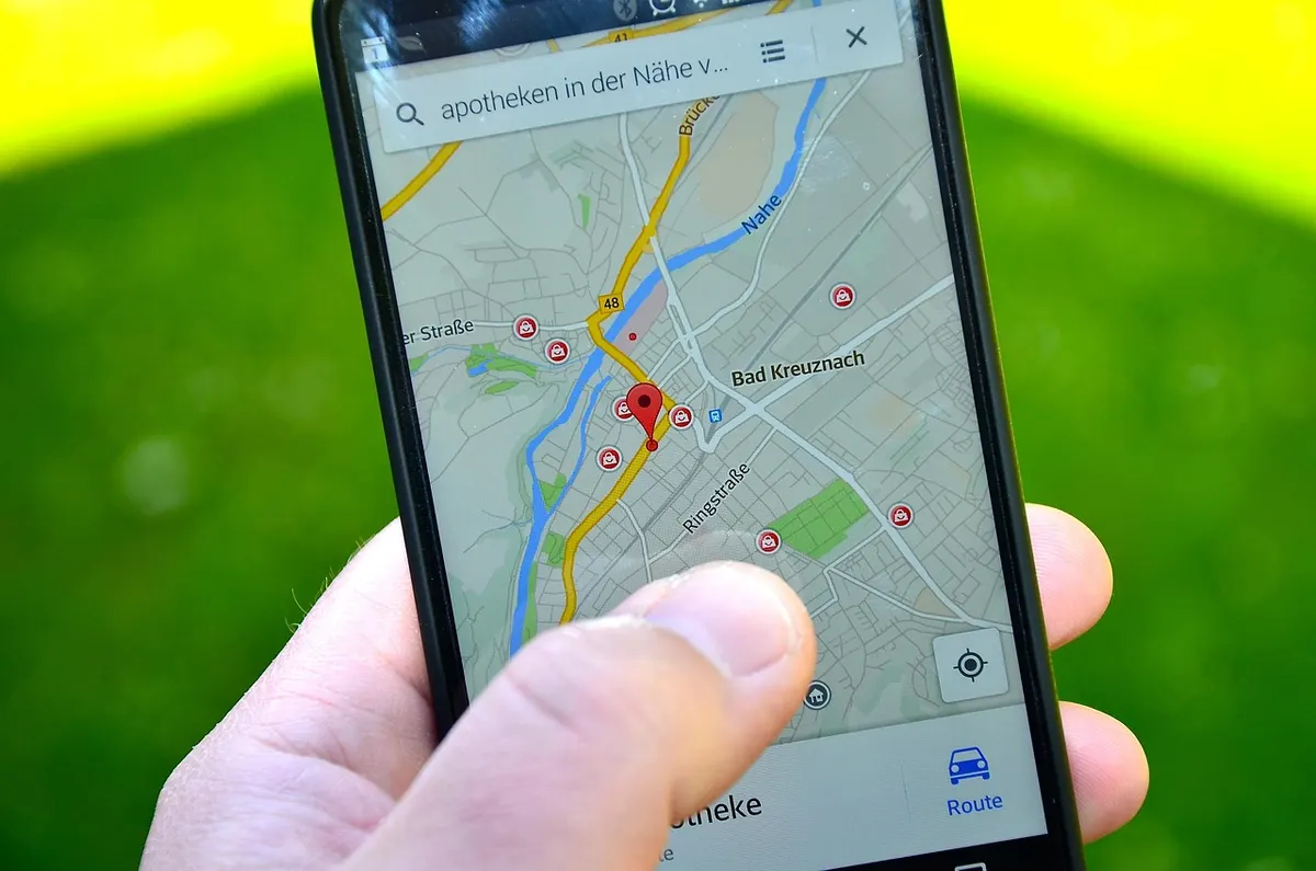 A hand holding a phone showing a map app with a red pin and nearby pharmacies, the kind of local search local SEO is about.