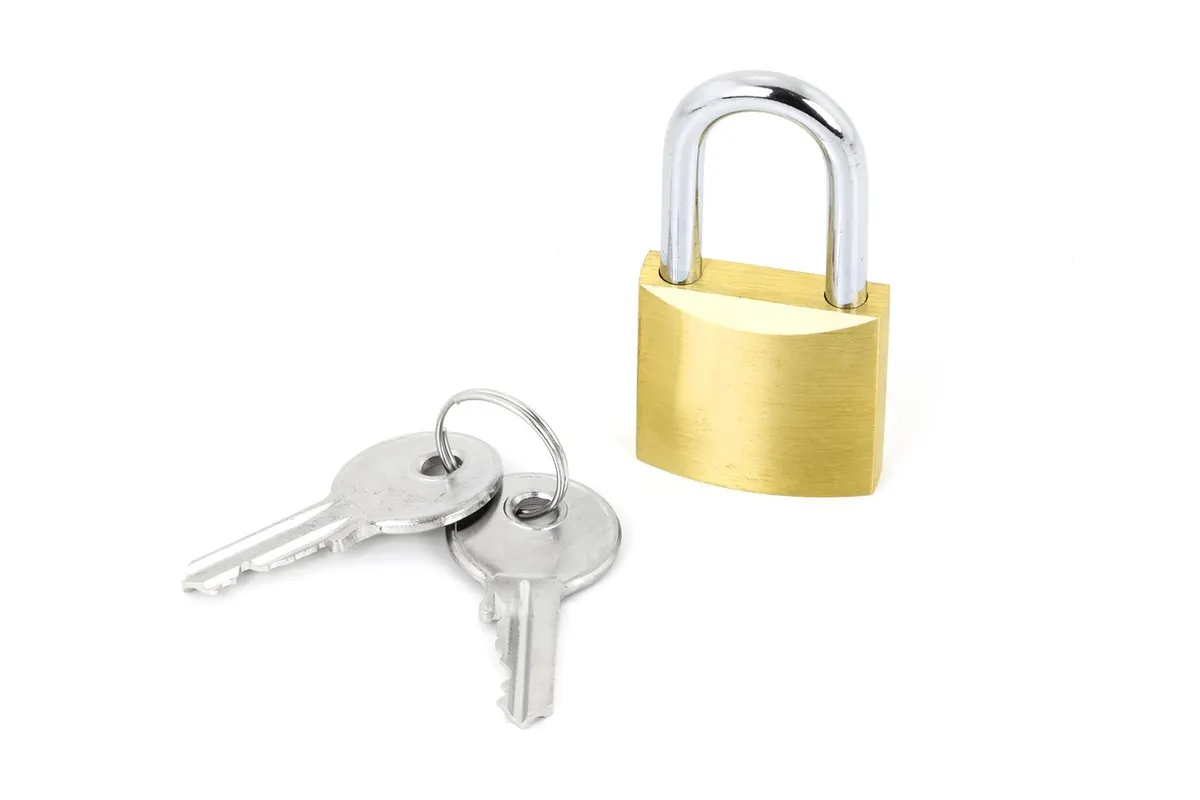 A brass padlock with two keys beside it on a white background