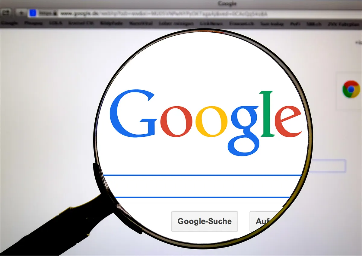 A magnifying glass held over the Google search page on a laptop screen.