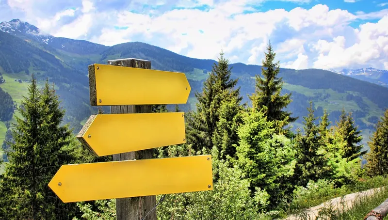 Yellow wooden signposts pointing in different directions on a mountain path