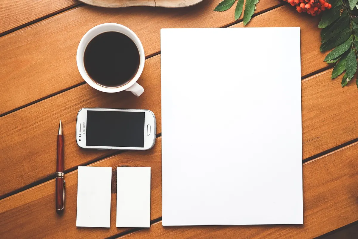 A flat lay of matching blank business stationery, including a letterhead, business cards, a notebook, a pen and a phone, showing the touchpoints a brand identity has to cover.