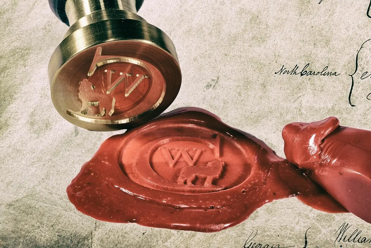 Brass stamp pressing a red wax seal onto a document, the old-fashioned version of a DKIM signature
