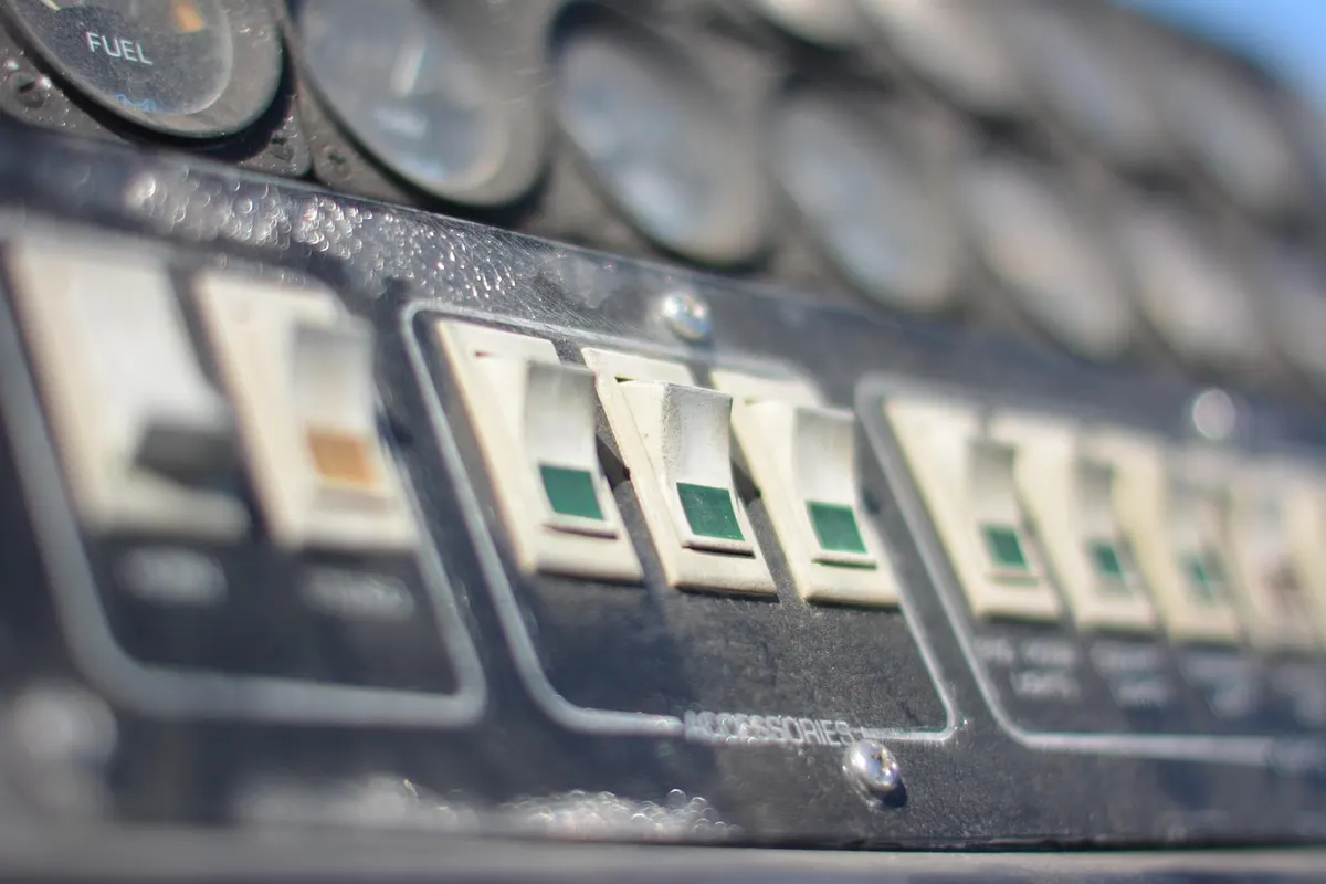 A row of labelled toggle switches beneath a set of dials on an old control panel, the physical version of a hosting dashboard.