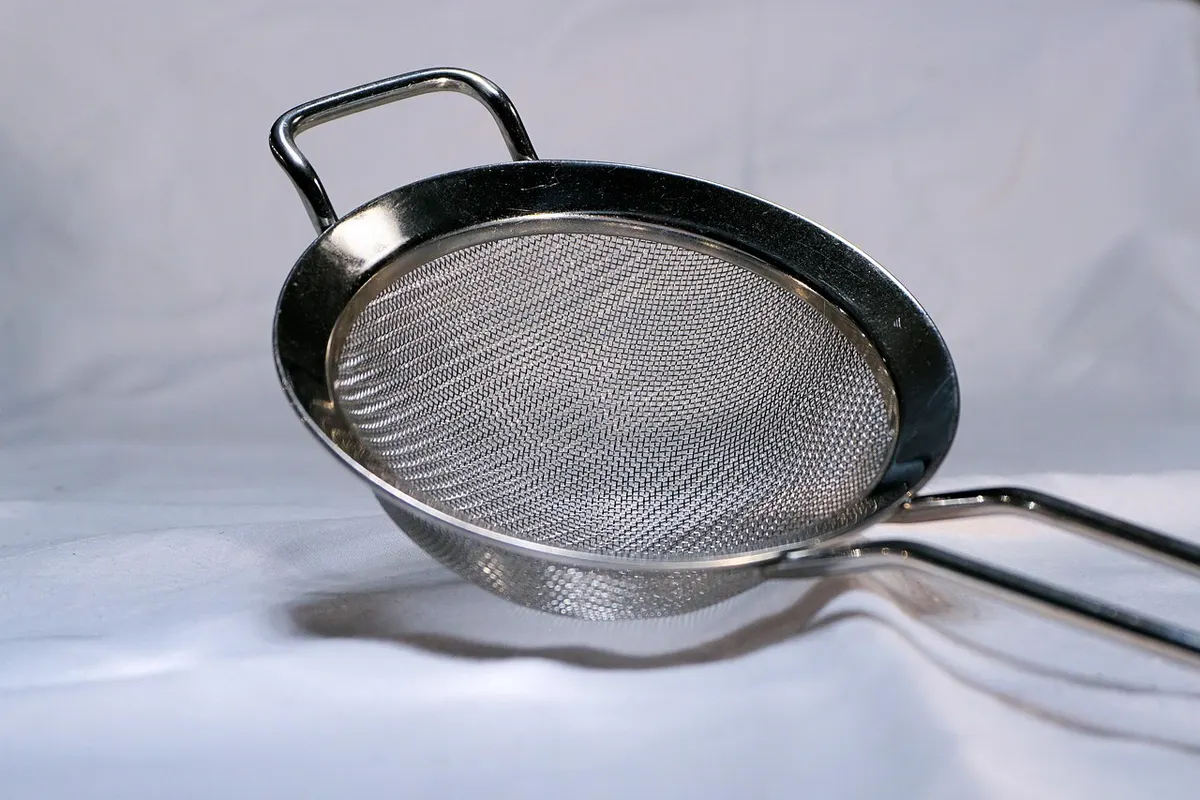 A stainless steel mesh sieve on a white cloth, which lets the fine stuff through and catches the lumps, much as a WAF filters web traffic.