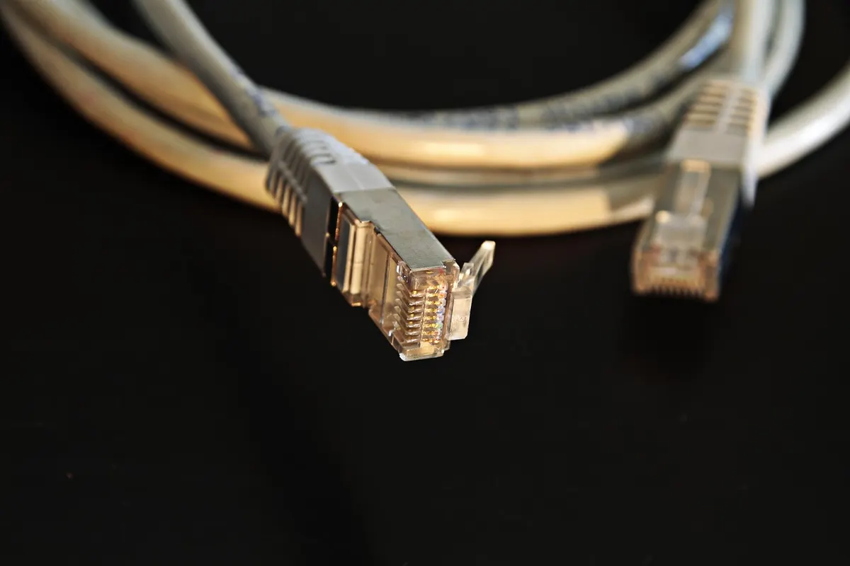 Two network cable plugs lying apart on a black background, a connection waiting to be made.