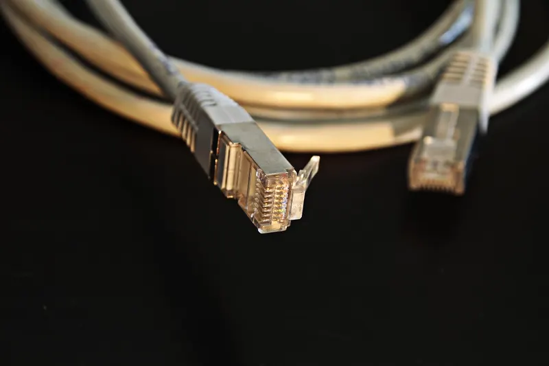 Two network cable plugs lying apart on a black background, a connection waiting to be made.