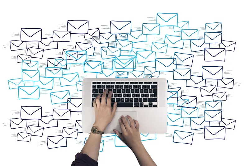 Hands typing on a keyboard as email envelopes fly out