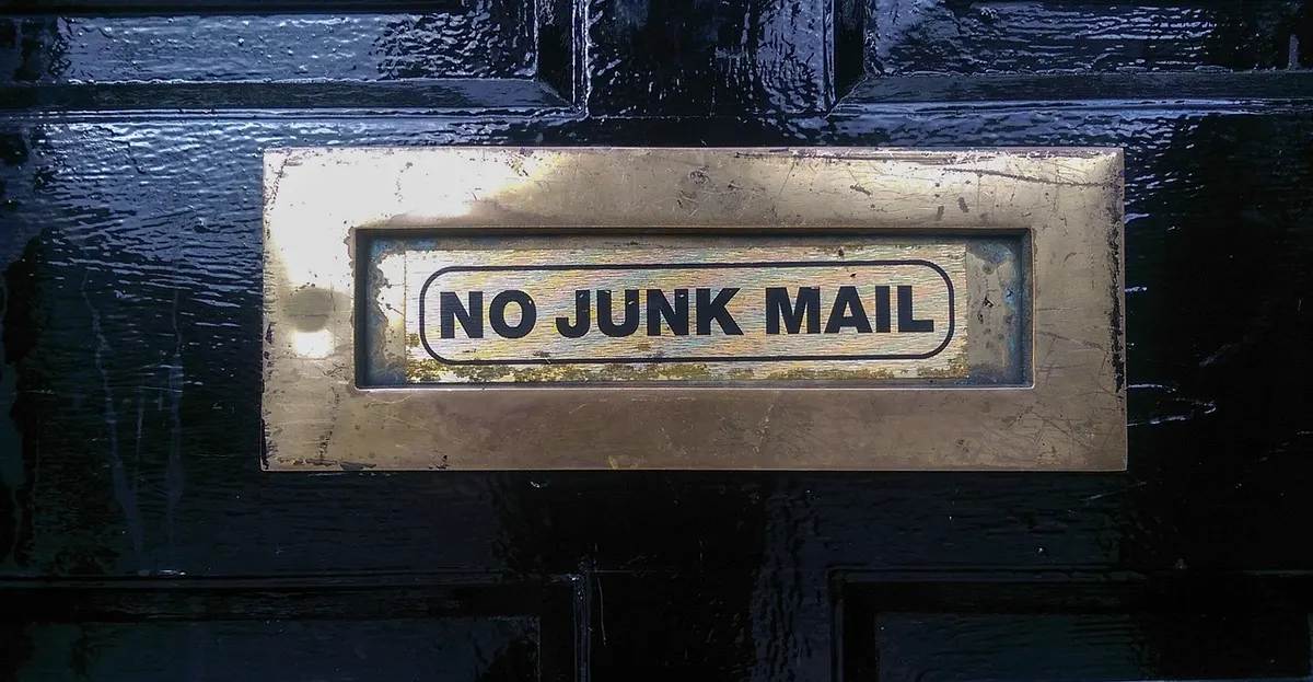 Brass letterbox on a dark door labelled "No junk mail"